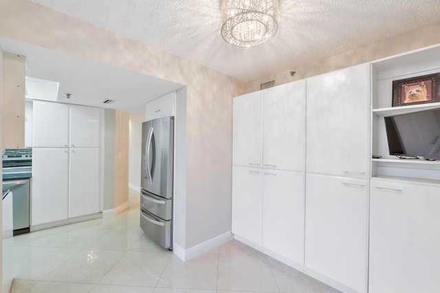 kitchen featuring stainless steel fridge, white cabinets, and a textured ceiling