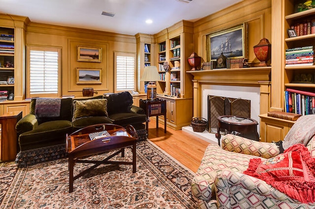 living room featuring crown molding, hardwood / wood-style floors, a wealth of natural light, and built in shelves