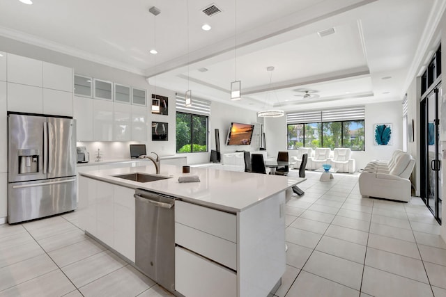 kitchen with a kitchen island with sink, white cabinetry, a tray ceiling, and stainless steel appliances