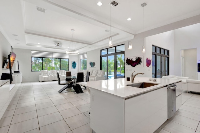 kitchen featuring hanging light fixtures, sink, an island with sink, and a tray ceiling