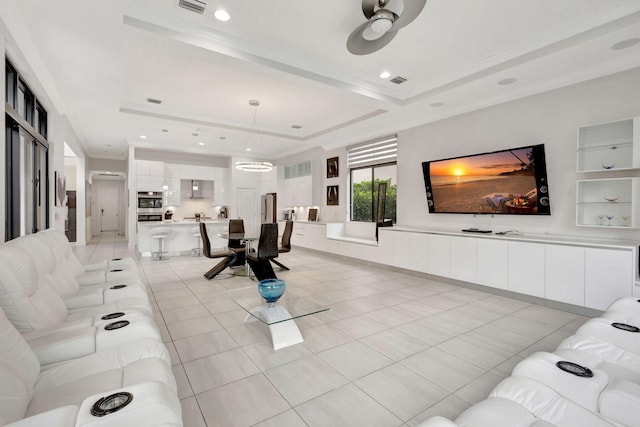 living room with a raised ceiling, ceiling fan, and light tile patterned floors