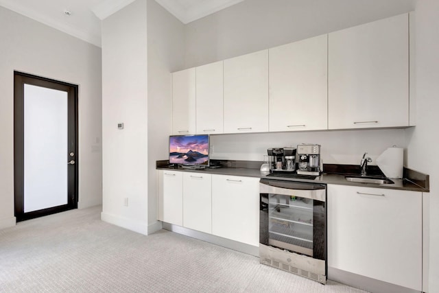 kitchen with wine cooler, white cabinetry, crown molding, and sink