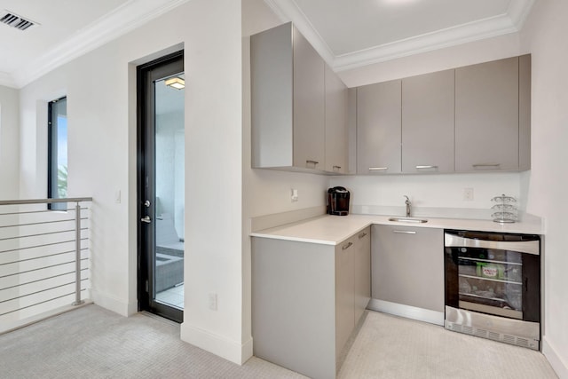 kitchen with sink, beverage cooler, gray cabinets, light carpet, and ornamental molding