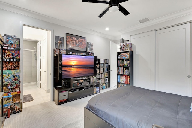 bedroom featuring a closet, ensuite bath, ceiling fan, and crown molding