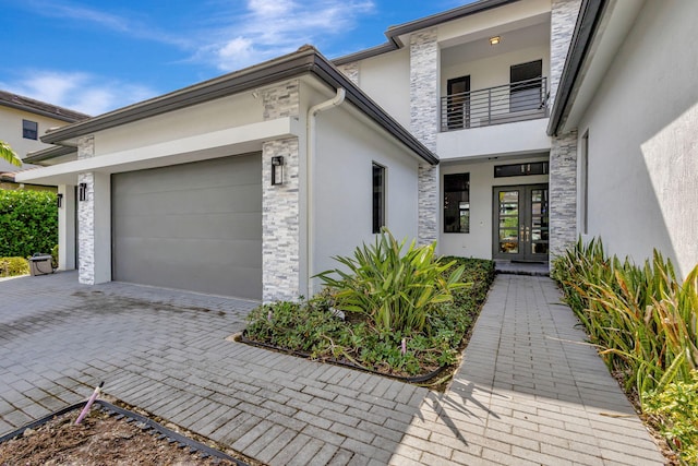 entrance to property with french doors, a balcony, and a garage