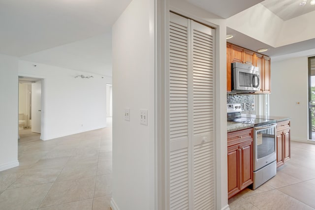 kitchen featuring tasteful backsplash, stainless steel appliances, stone countertops, and light tile patterned floors