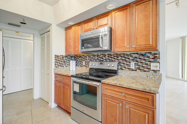 kitchen featuring light stone countertops, appliances with stainless steel finishes, tasteful backsplash, and light tile patterned flooring