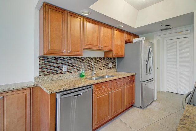 kitchen with tasteful backsplash, sink, stainless steel appliances, light stone counters, and light tile patterned floors