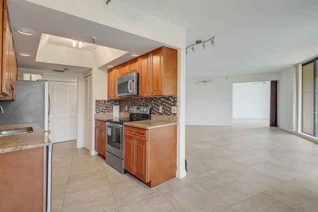 kitchen with stainless steel appliances, backsplash, sink, light tile patterned flooring, and a raised ceiling