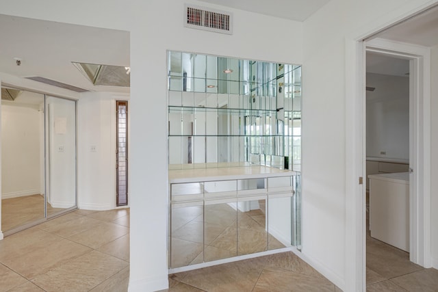 interior space featuring washer / clothes dryer, light tile patterned flooring, and white cabinets