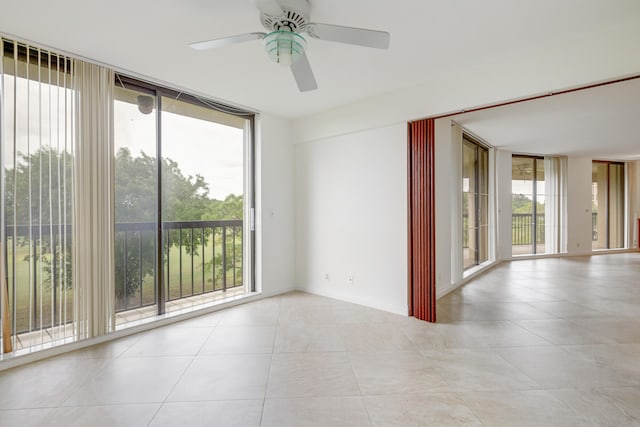 spare room featuring ceiling fan, light tile patterned floors, floor to ceiling windows, and a wealth of natural light