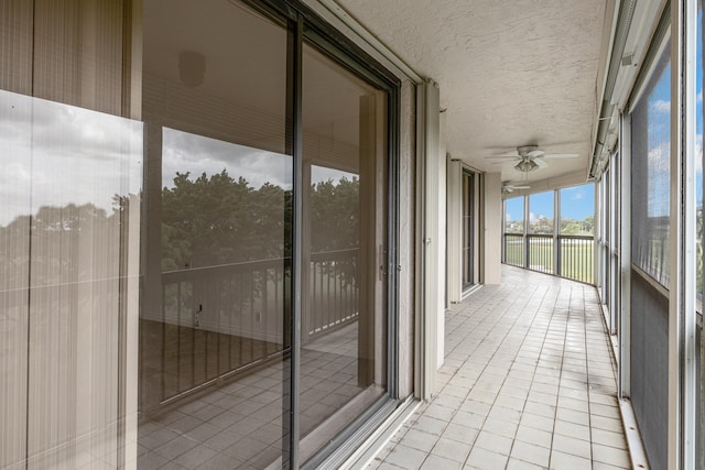 unfurnished sunroom featuring ceiling fan