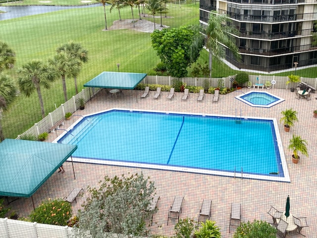 view of swimming pool featuring a patio, a hot tub, a yard, and a water view