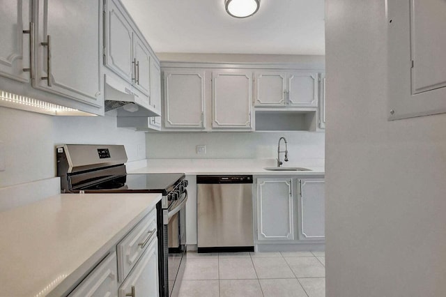 kitchen featuring sink, light tile patterned flooring, stainless steel appliances, white cabinets, and electric panel