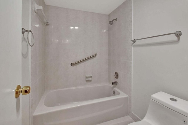 bathroom featuring toilet and tiled shower / bath