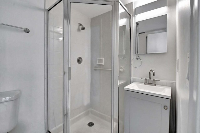 bathroom with a shower with door, vanity, and toilet