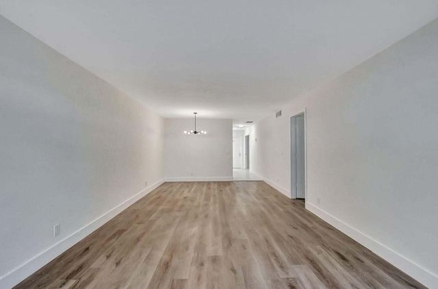 unfurnished room featuring a notable chandelier and light hardwood / wood-style floors