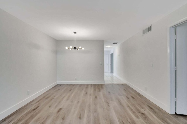 empty room featuring light hardwood / wood-style floors and a notable chandelier