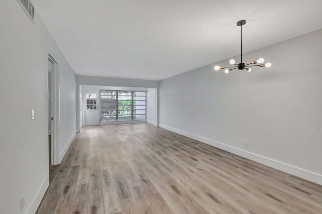 unfurnished living room featuring light hardwood / wood-style floors and a chandelier