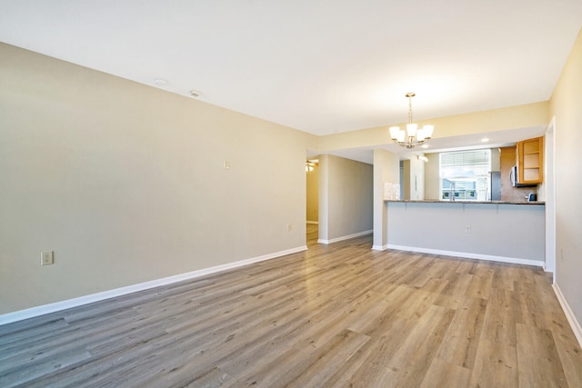 unfurnished living room with light hardwood / wood-style floors and a notable chandelier