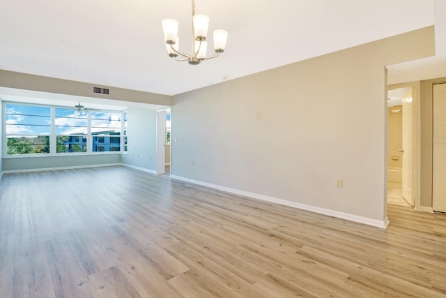 spare room with a notable chandelier and light wood-type flooring