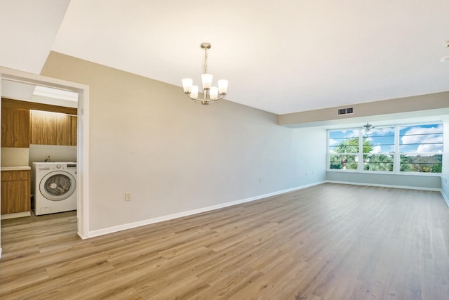 spare room with a notable chandelier, light hardwood / wood-style floors, and washer / clothes dryer