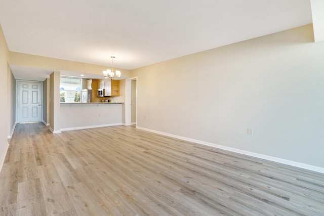 unfurnished living room with a chandelier and light hardwood / wood-style floors