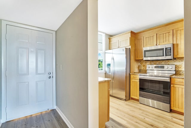 kitchen with light hardwood / wood-style floors, tasteful backsplash, stainless steel appliances, and light brown cabinetry