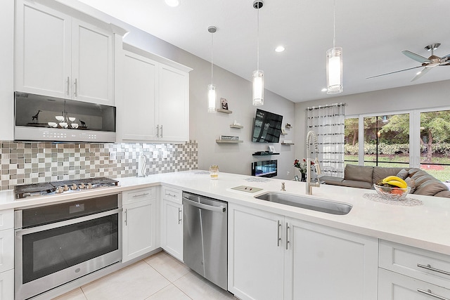 kitchen featuring appliances with stainless steel finishes, white cabinets, sink, and hanging light fixtures