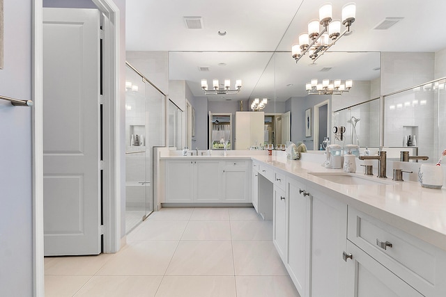 bathroom with a shower with door, vanity, and tile patterned flooring