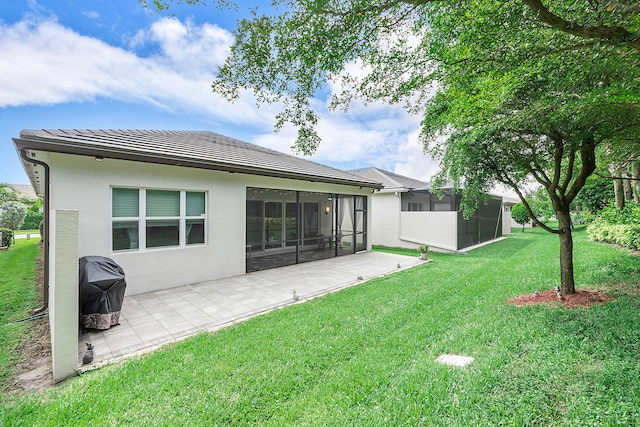 rear view of property with a yard, a patio area, and a sunroom