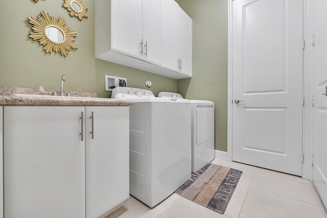 washroom with sink, washer and dryer, light tile patterned floors, and cabinets