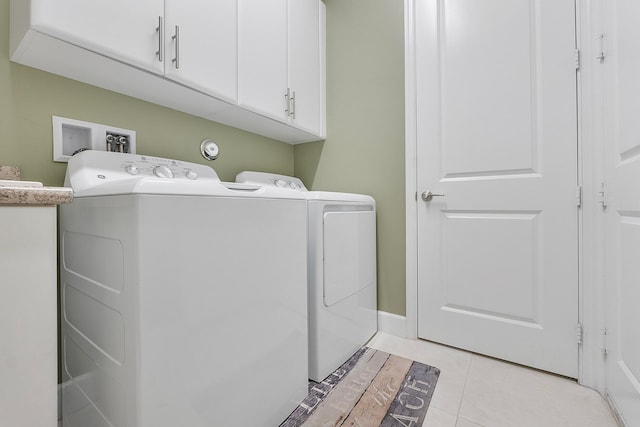 laundry room with cabinets, light tile patterned flooring, and washer and clothes dryer