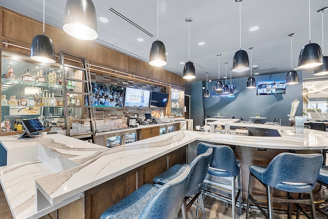 bar with decorative light fixtures and light stone counters