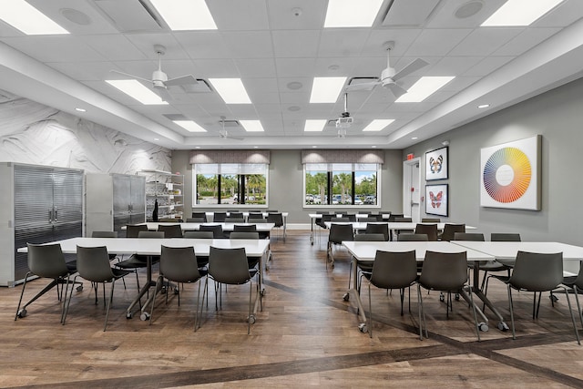 dining space with a drop ceiling, hardwood / wood-style floors, and ceiling fan