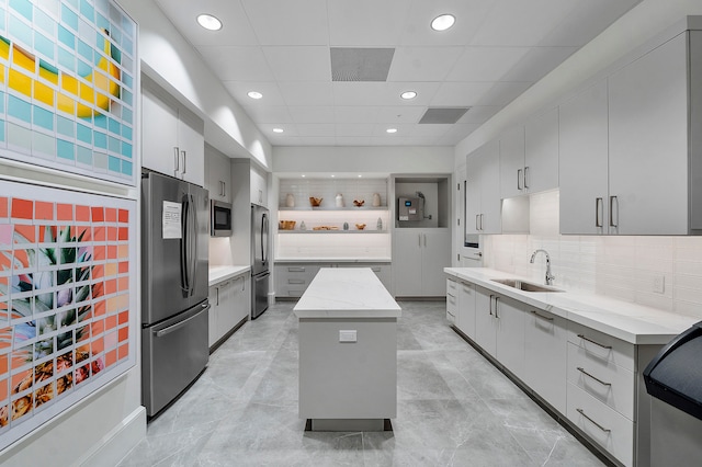 kitchen featuring appliances with stainless steel finishes, sink, a kitchen island, backsplash, and gray cabinets