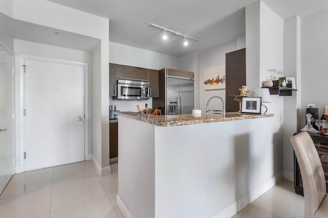 kitchen featuring stainless steel appliances, dark brown cabinets, a textured ceiling, and kitchen peninsula