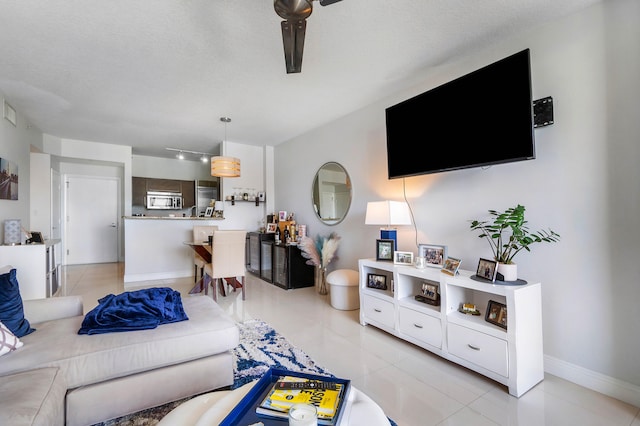 living room featuring ceiling fan, a textured ceiling, and light tile patterned floors