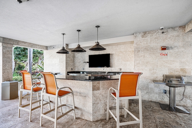 kitchen with a breakfast bar, a textured ceiling, decorative light fixtures, and tile walls