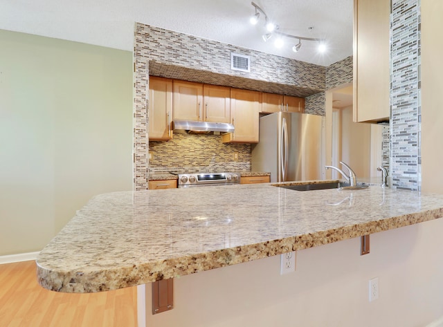 kitchen featuring a kitchen bar, appliances with stainless steel finishes, decorative backsplash, and wood-type flooring