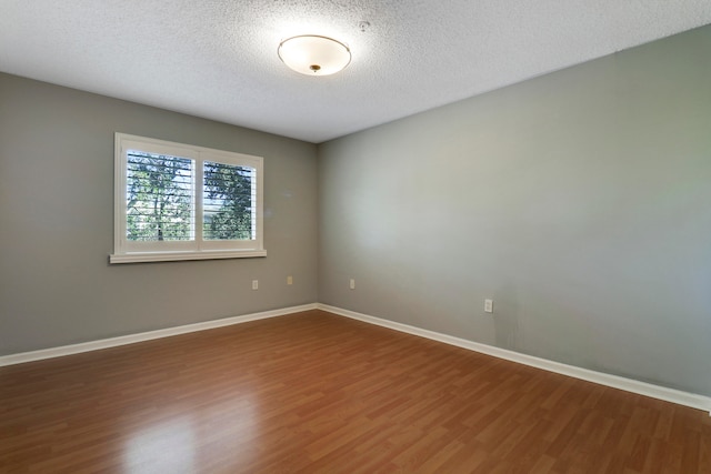 empty room with dark wood-type flooring and a textured ceiling