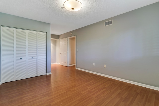 unfurnished bedroom featuring a closet, a textured ceiling, and hardwood / wood-style flooring