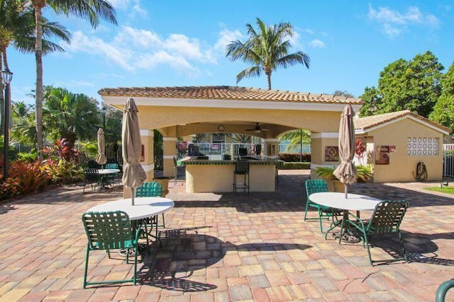 view of patio with a gazebo, ceiling fan, and exterior bar