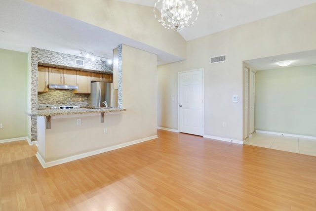 unfurnished room with a notable chandelier, light hardwood / wood-style floors, and high vaulted ceiling