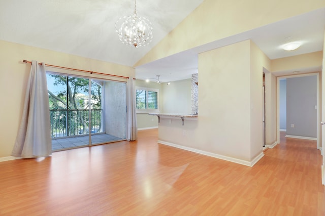 empty room featuring high vaulted ceiling, light hardwood / wood-style floors, and an inviting chandelier