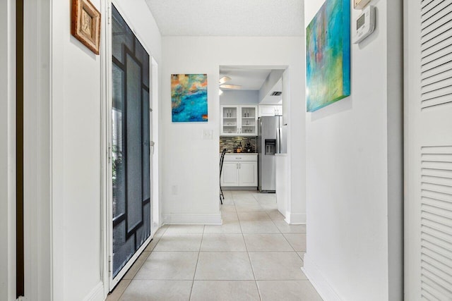 corridor featuring a textured ceiling and light tile patterned floors