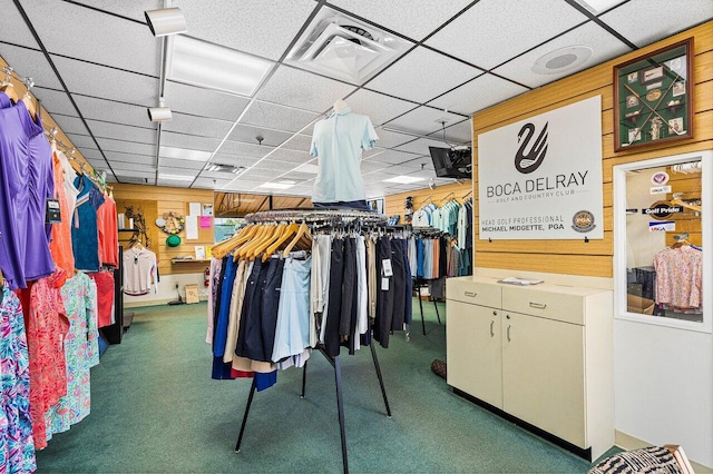 walk in closet with a drop ceiling and dark colored carpet