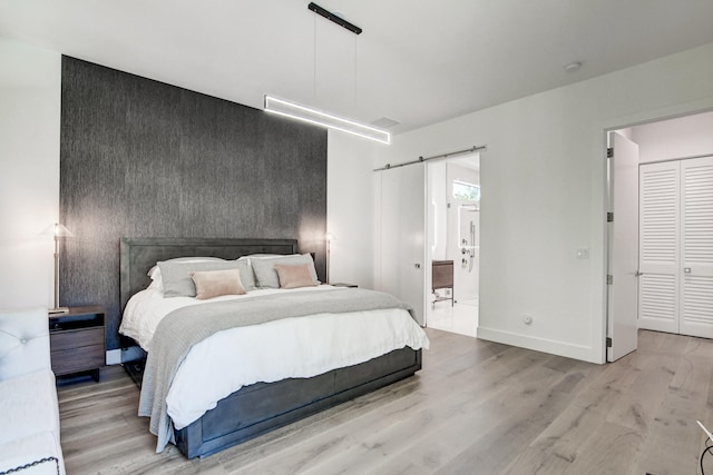 bedroom with light hardwood / wood-style flooring and a barn door