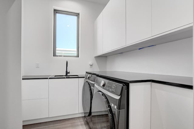 laundry area with sink, washing machine and clothes dryer, light wood-type flooring, and cabinets