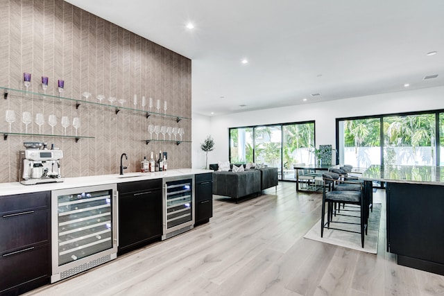 bar featuring sink, light hardwood / wood-style flooring, and beverage cooler